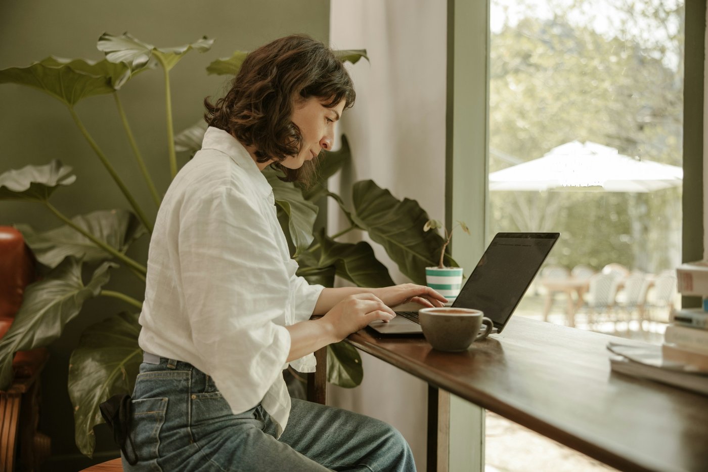 Frau arbeitet konzentriert am Laptop in einem Café – Coaching Business aufbauen trotz innerer Blockaden